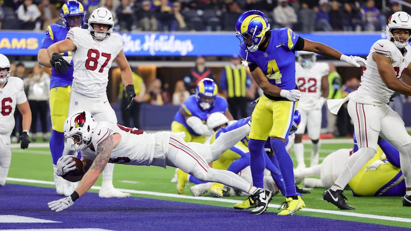 Arizona Cardinals tight end Trey McBride, left, lunges into the end zone for a touchdown...