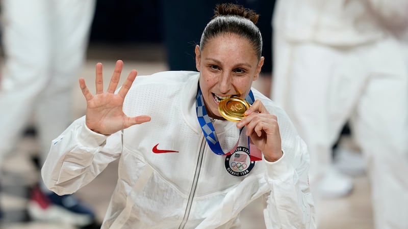 FILE - United States's Diana Taurasi bites her gold medal during the medal ceremony for...