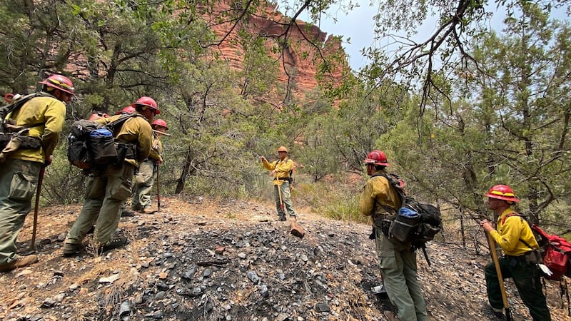 In this photo provided by the U.S. Forest Service, Jason Nez, center, talks to wildland fire...