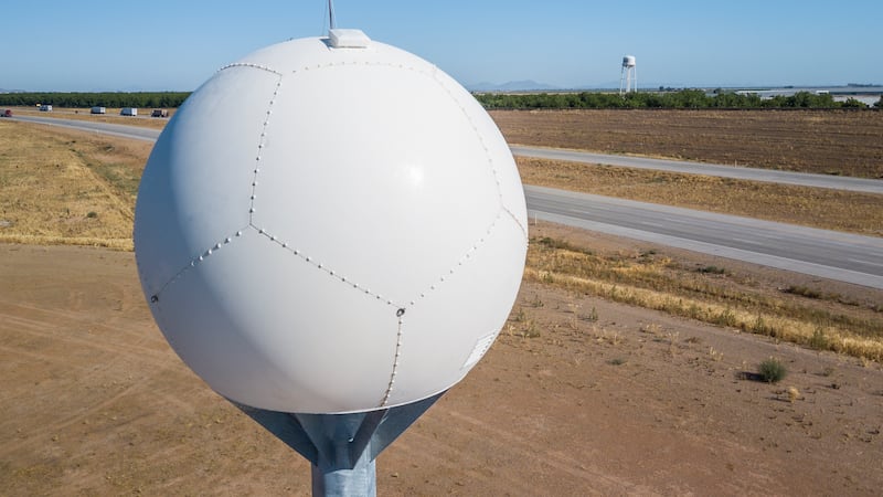 Round ball-like X Band radar site sits atop of a tall metal pole next to the interstate 10 in...