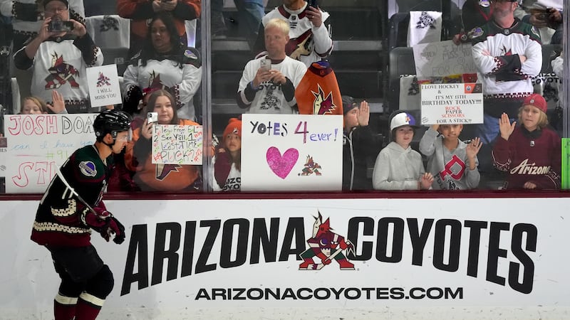 Arizona Coyotes' Dylan Guenther skates past fans as players warm up for an NHL hockey game...
