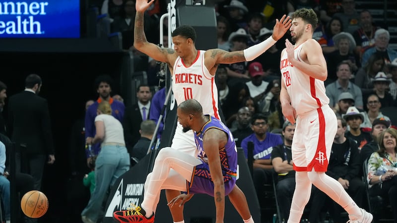 Phoenix Suns forward Kevin Durant, center, sprains an ankle as the drives to the basket...