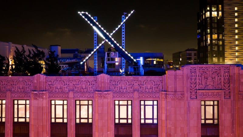 FILE - Workers install lighting on an "X" sign atop the company headquarters, formerly known...