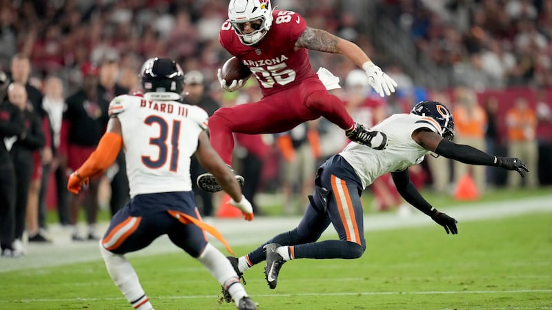 Arizona Cardinals tight end Trey McBride leaps over the defender as Chicago Bears safety Kevin...